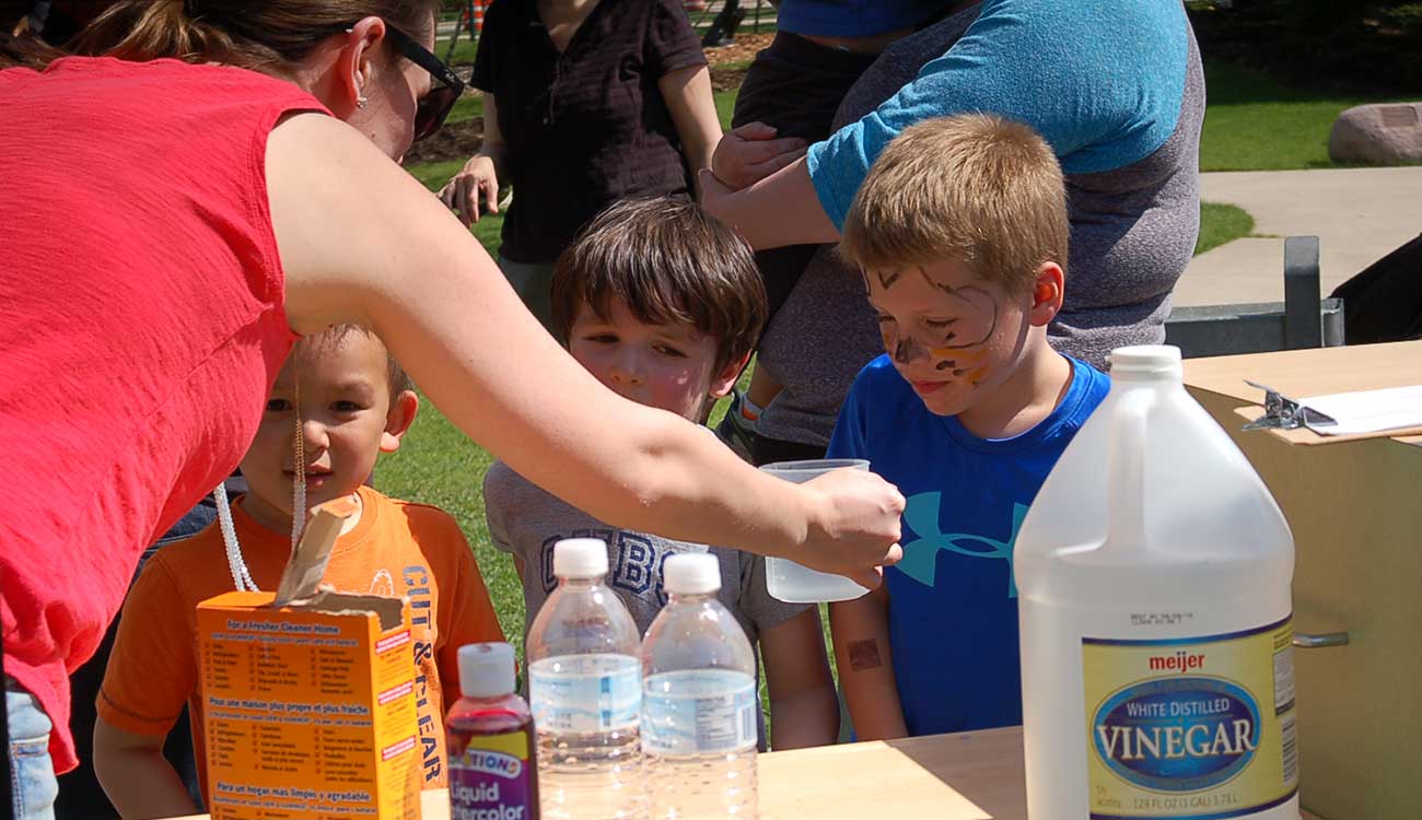 Woman helping children with science experiment, Robin Andrews