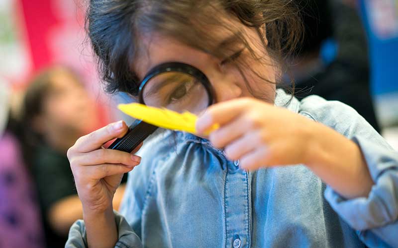 Child looking through magnifying glass